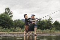 Miles Johnson and his toddler holding a fishing rod on a river bank