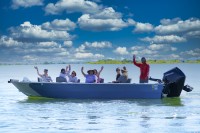 [Image of 8 people waving from a fishing motorboat on the Hanford Reach during a Hanford Journey boat tour.]