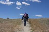 Photo of two people hiking a path across the Columbia River from Hanford on a sunny day.