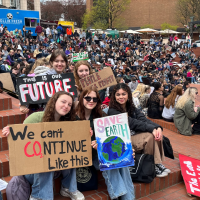 Photo of student activists in a crowd holding signs that say environmental justice slogans