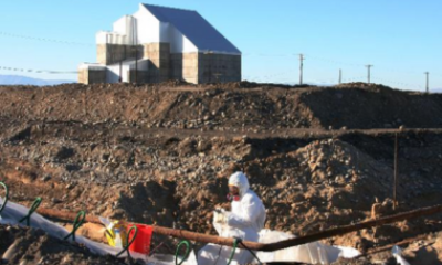 Image of worker at Hanford with hazmat suit on digging in front of a reactor