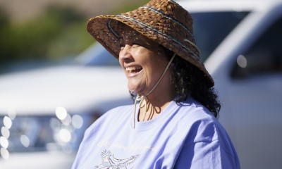 Photo of woman, laurene, smiling. She is wearing a traditional woven hat that blocks her eyes from sun