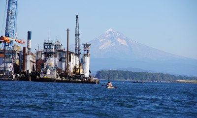 Columbia River near Vancouver, Washington showing water, mountain, and industry with a small kayaker in the background.